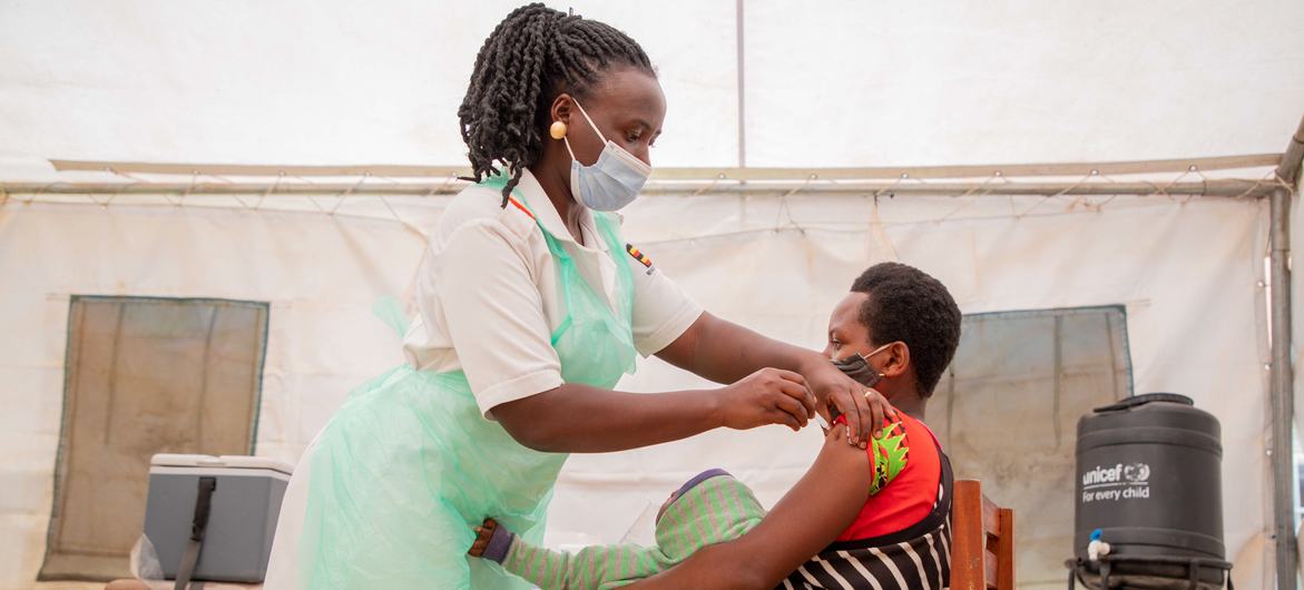 在乌干达的一个健康中心，一名护士给一名妇女注射新冠疫苗。